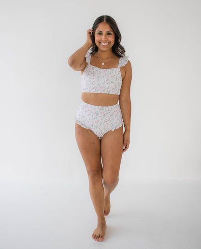 Woman wearing a white floral two-piece set against a plain background